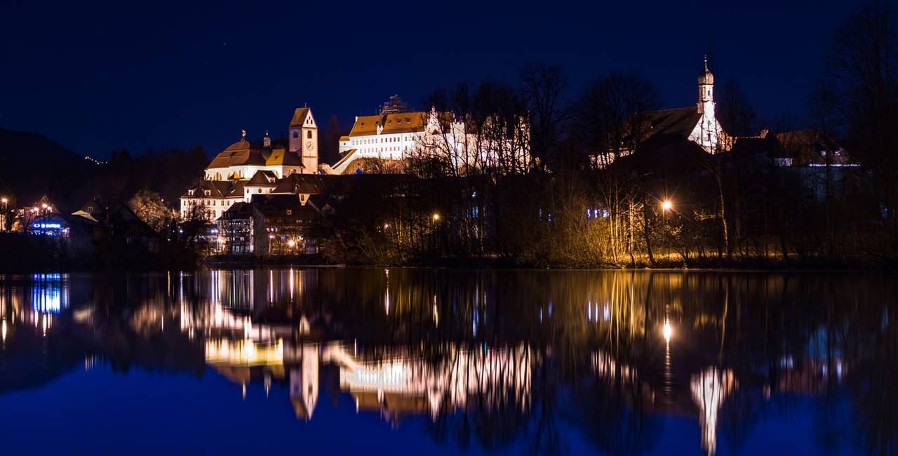 Blick auf das Hohe Schloss in der romantischen Füssener Altstadt bei Nacht.